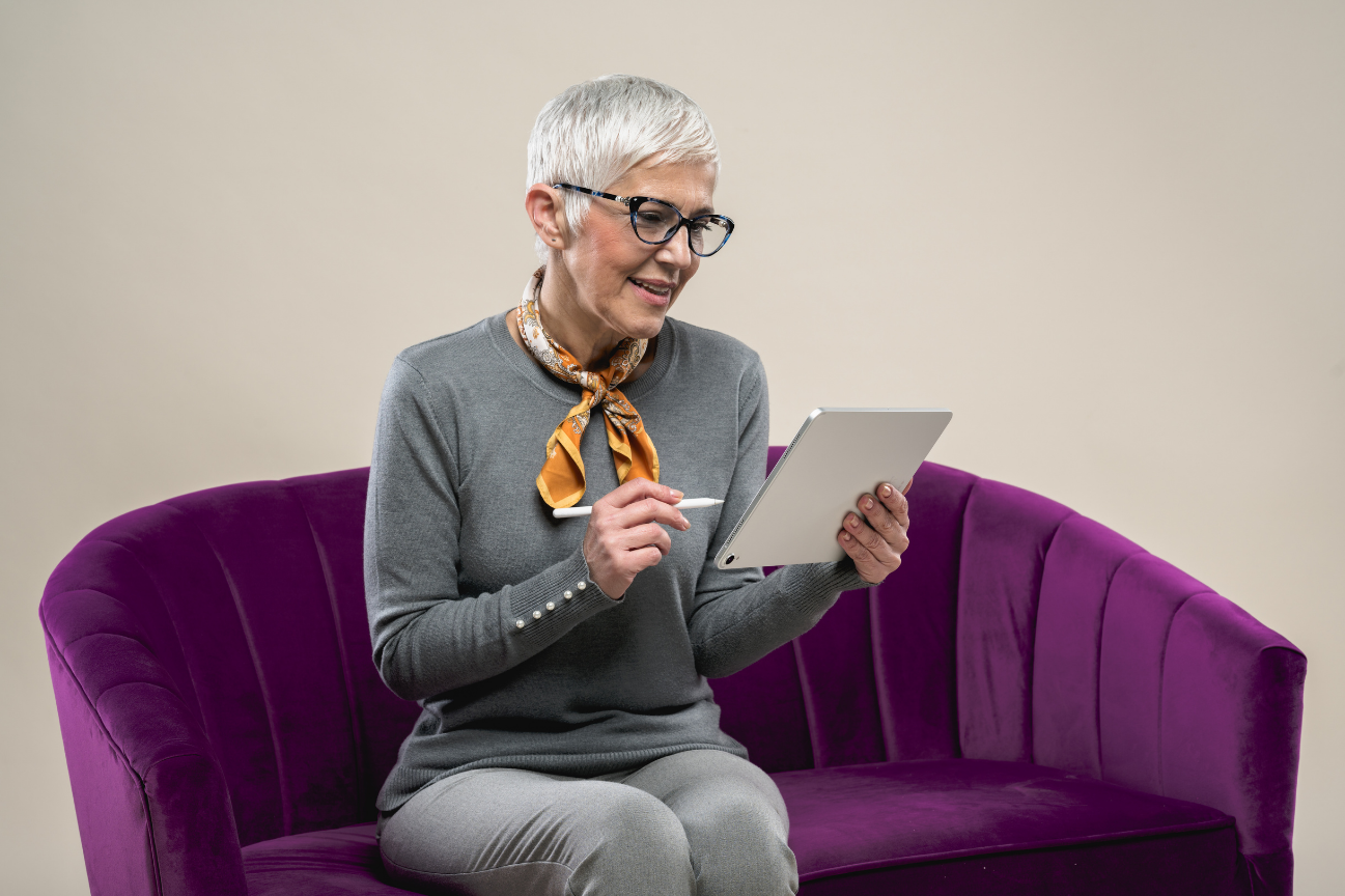 A grey-haired woman on an iPad with an Apple Pencil