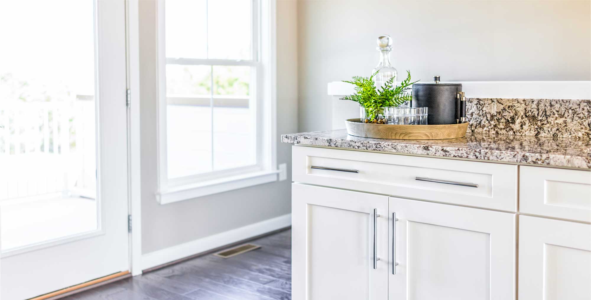 Modern, clean kitchen with granite countertop cabinets, serving tray and door to balcony.