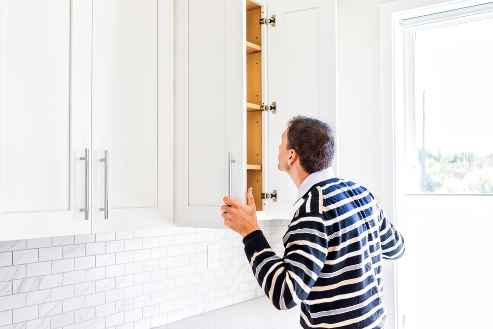 Man looking inside cabinet during home inspection.