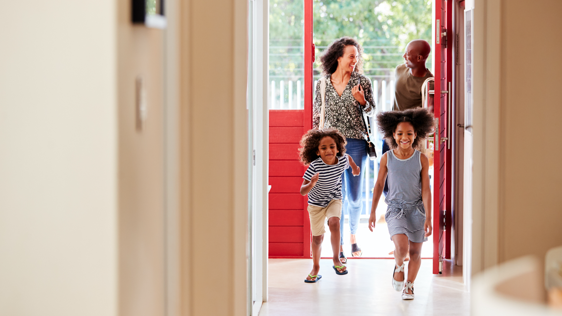 Family entering home with children excitedly running.