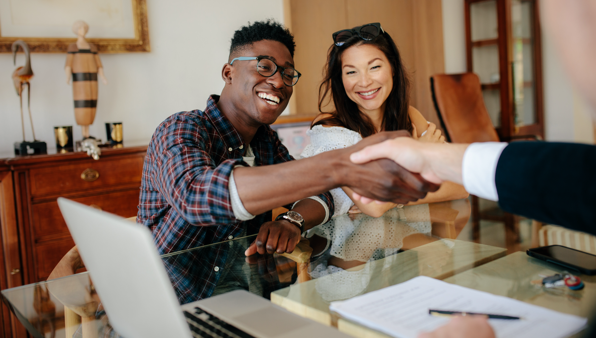 First-Time Homebuyer couple shakes hand with real estate agent.