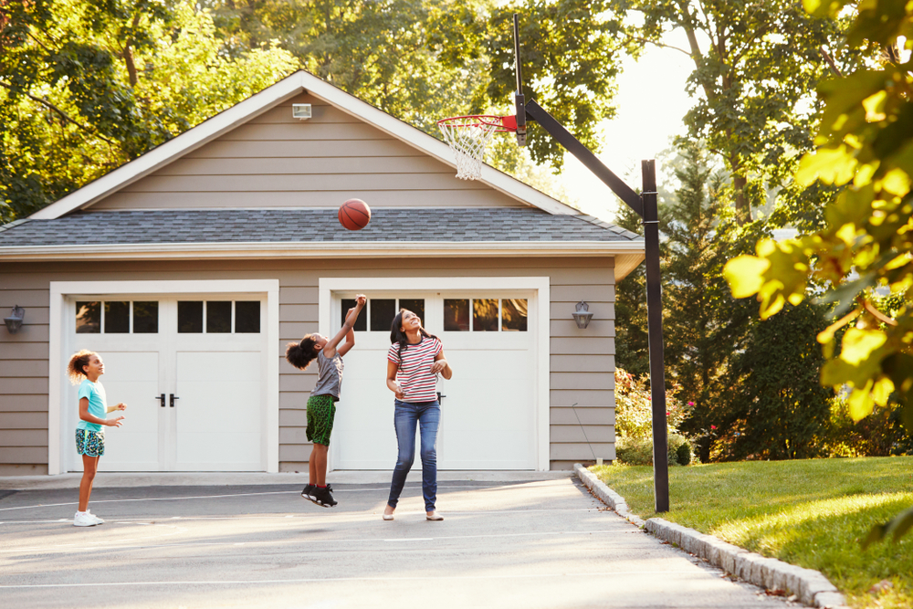 Family playing basketball in driveway.