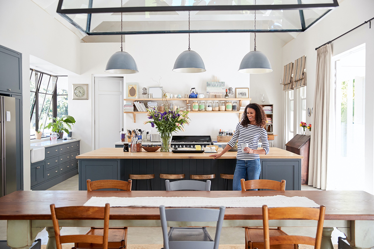 Woman leaning on kitchen island in open plan home.