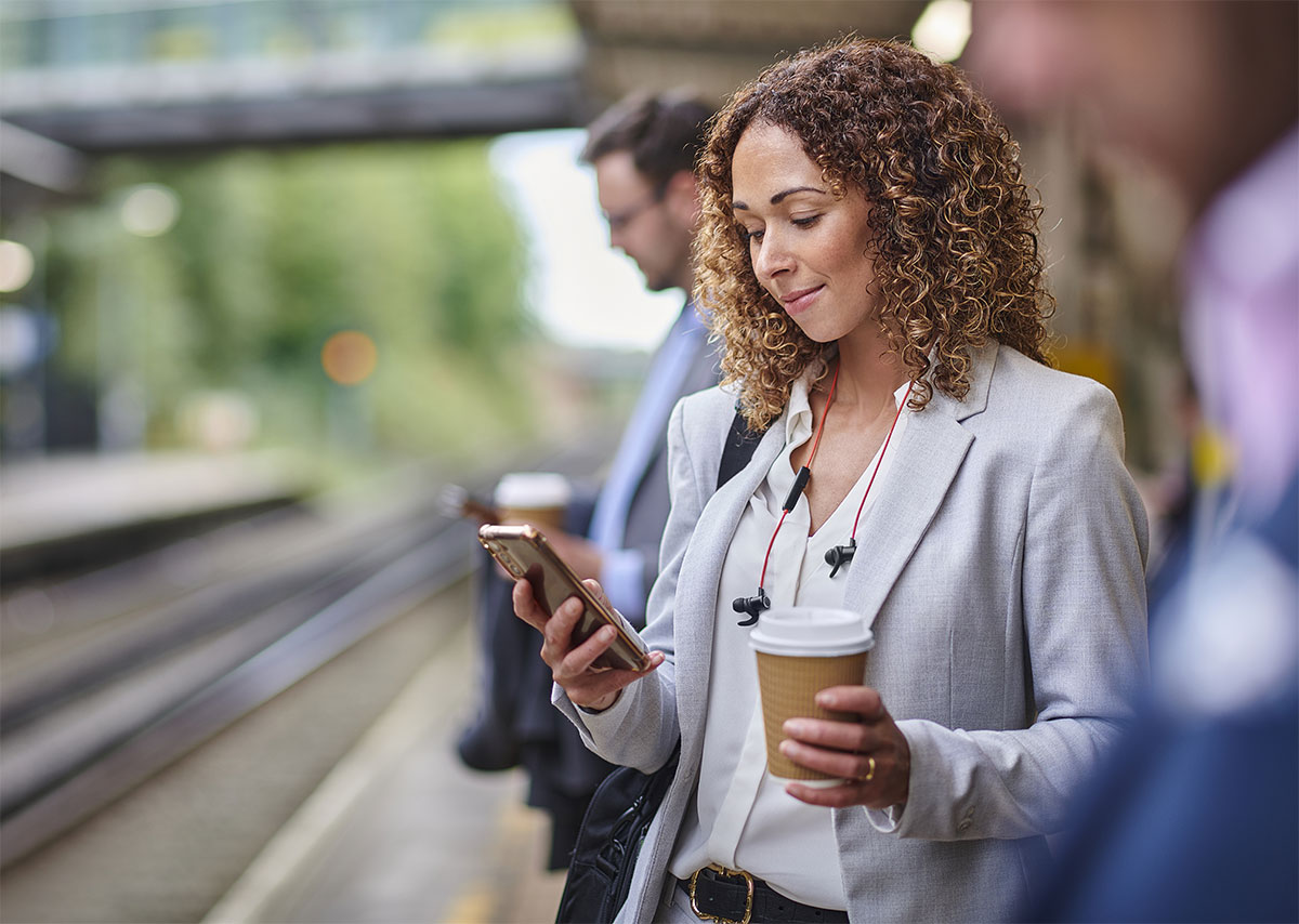 commuter looking at mobile phone while waiting at station