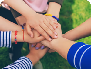 Kids putting their hands in a circle.