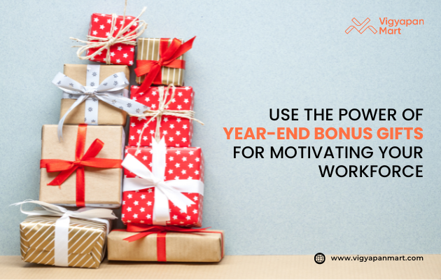 Stack of Christmas and year-end bonus gift boxes wrapped in red, gold, and patterned paper with festive ribbons. Promotional banner for Vigyapan Mart with text: "Use the power of year-end bonus gifts for motivating your workforce." Website: www.vigyapanmart.com