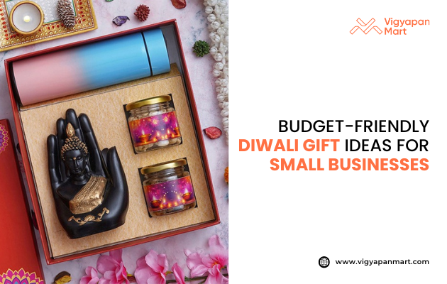 Budget-friendly Diwali gift hamper for small businesses, featuring a decorative Buddha hand statue, two scented candles in glass jars with colorful starry designs, and a gradient blue-pink insulated tumbler, presented in a festive gift box with flowers and diya decor. Branding includes Vigyapan Mart logo and website www.vigyapanmart.com