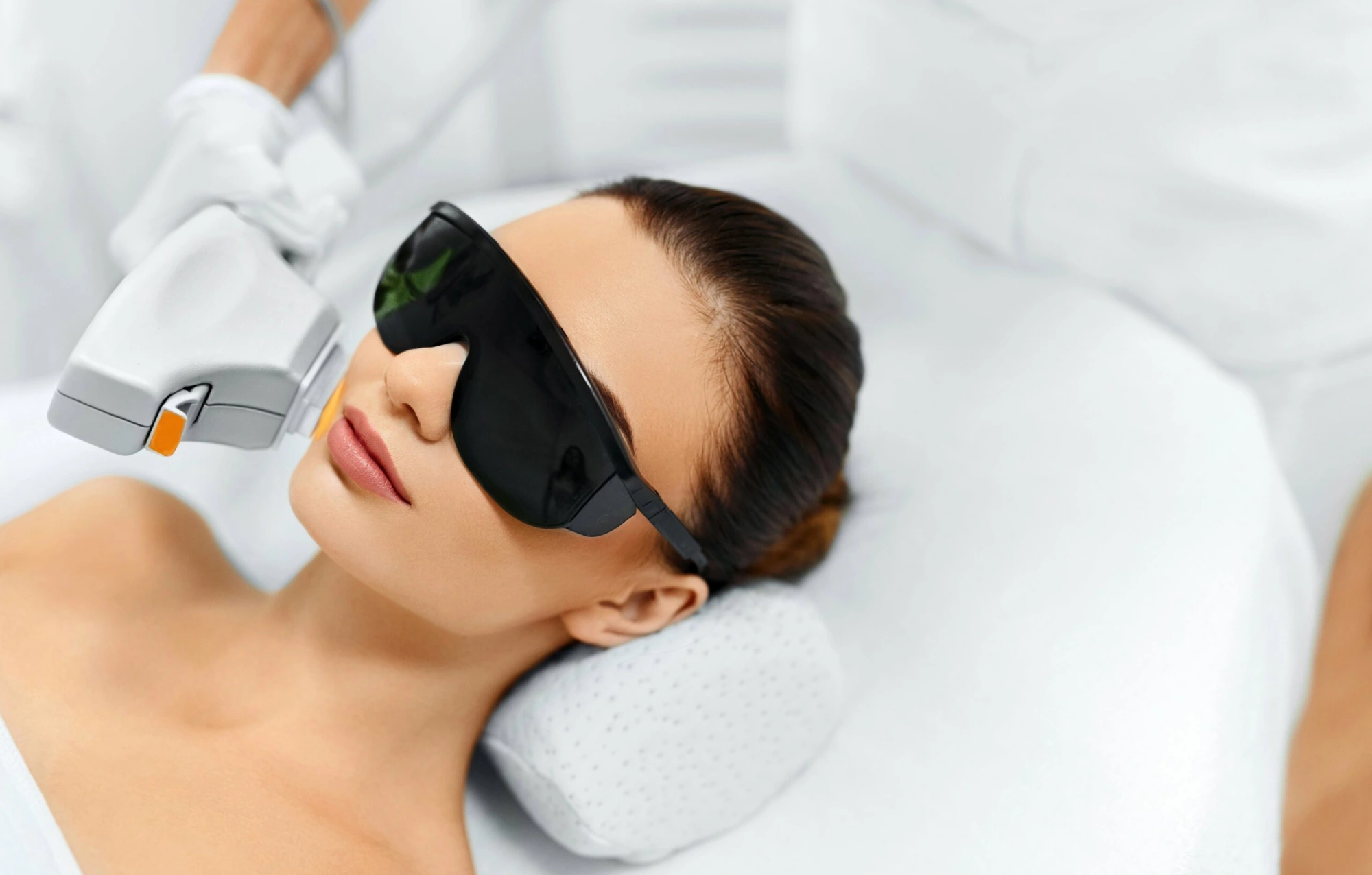 Close-up of a woman receiving an IPL photofacial treatment on her cheek.