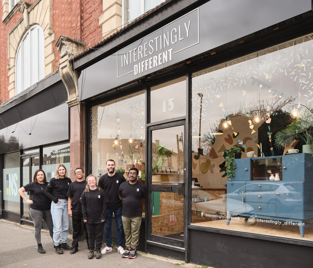 A group of people posing in front of a shopwindow.