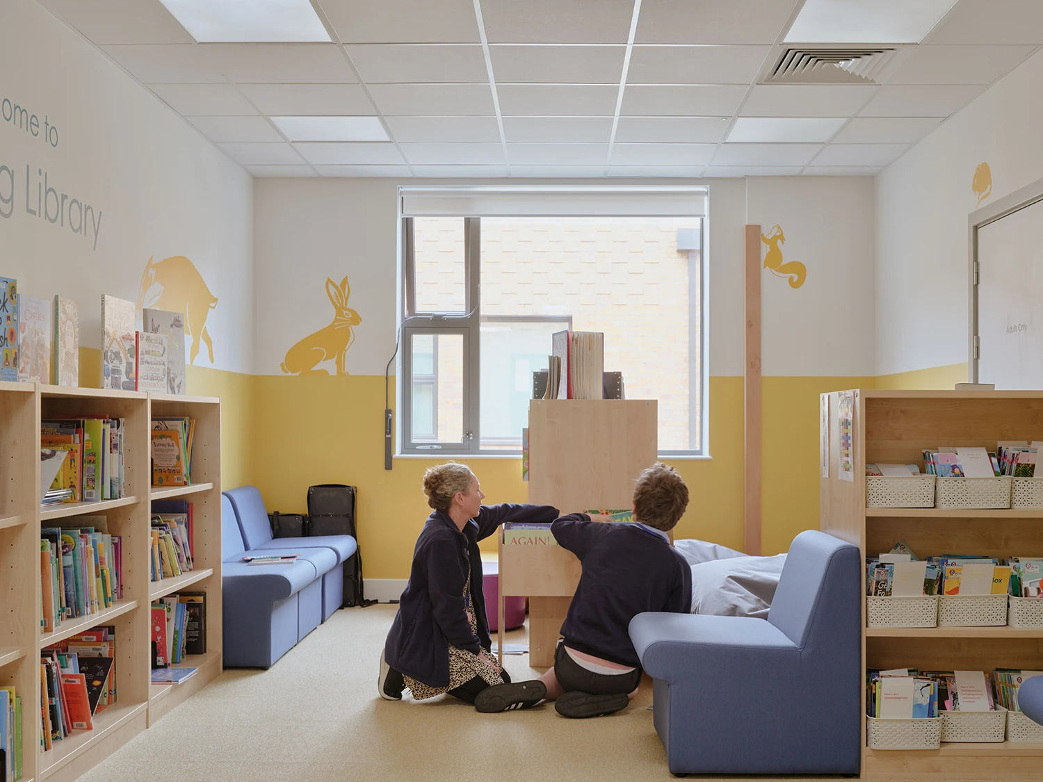 Staff member and student looking through books in school's library.