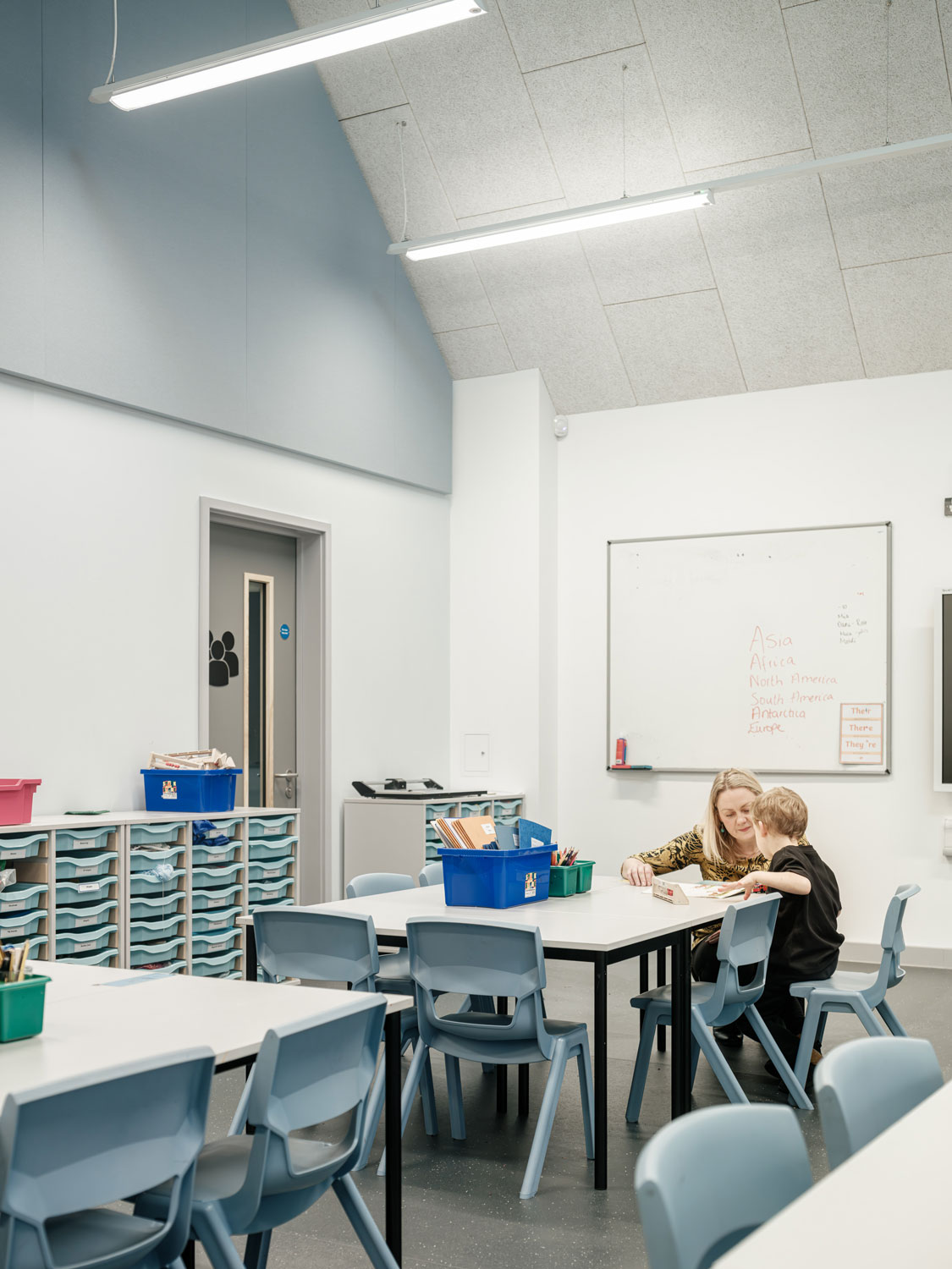 A student sat at a table in one of the new classrooms, drawing with an adult.