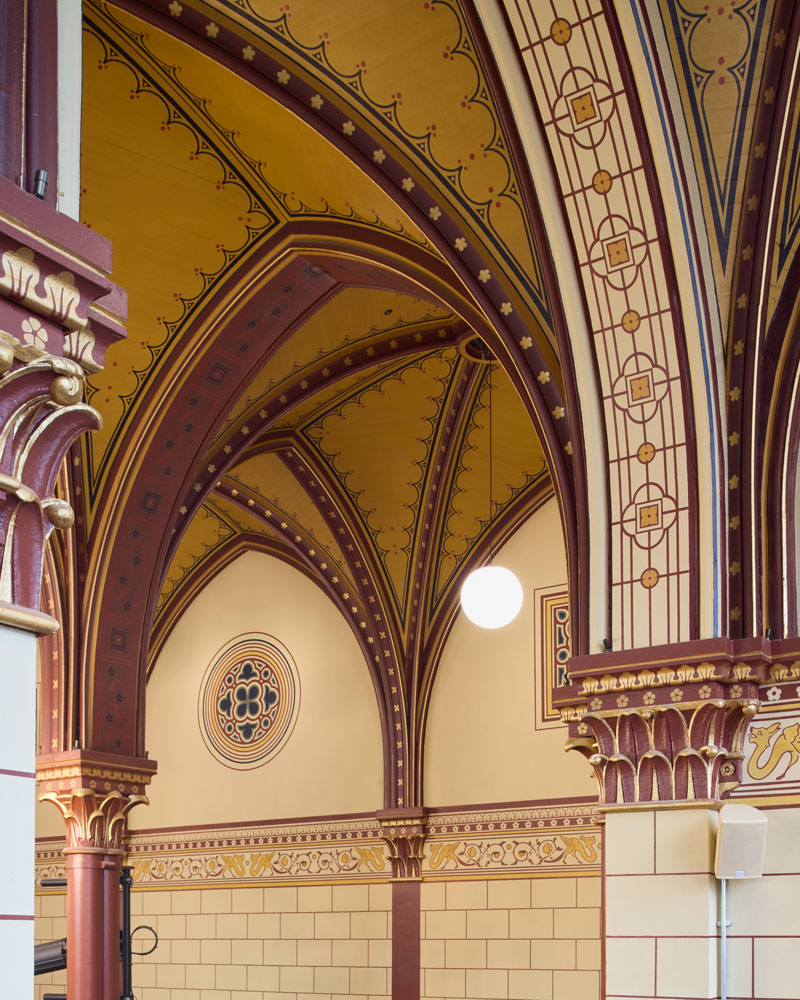 A close up-detail of the repainted decoration, with motifs painted in burgundy, orange, beige and gold.