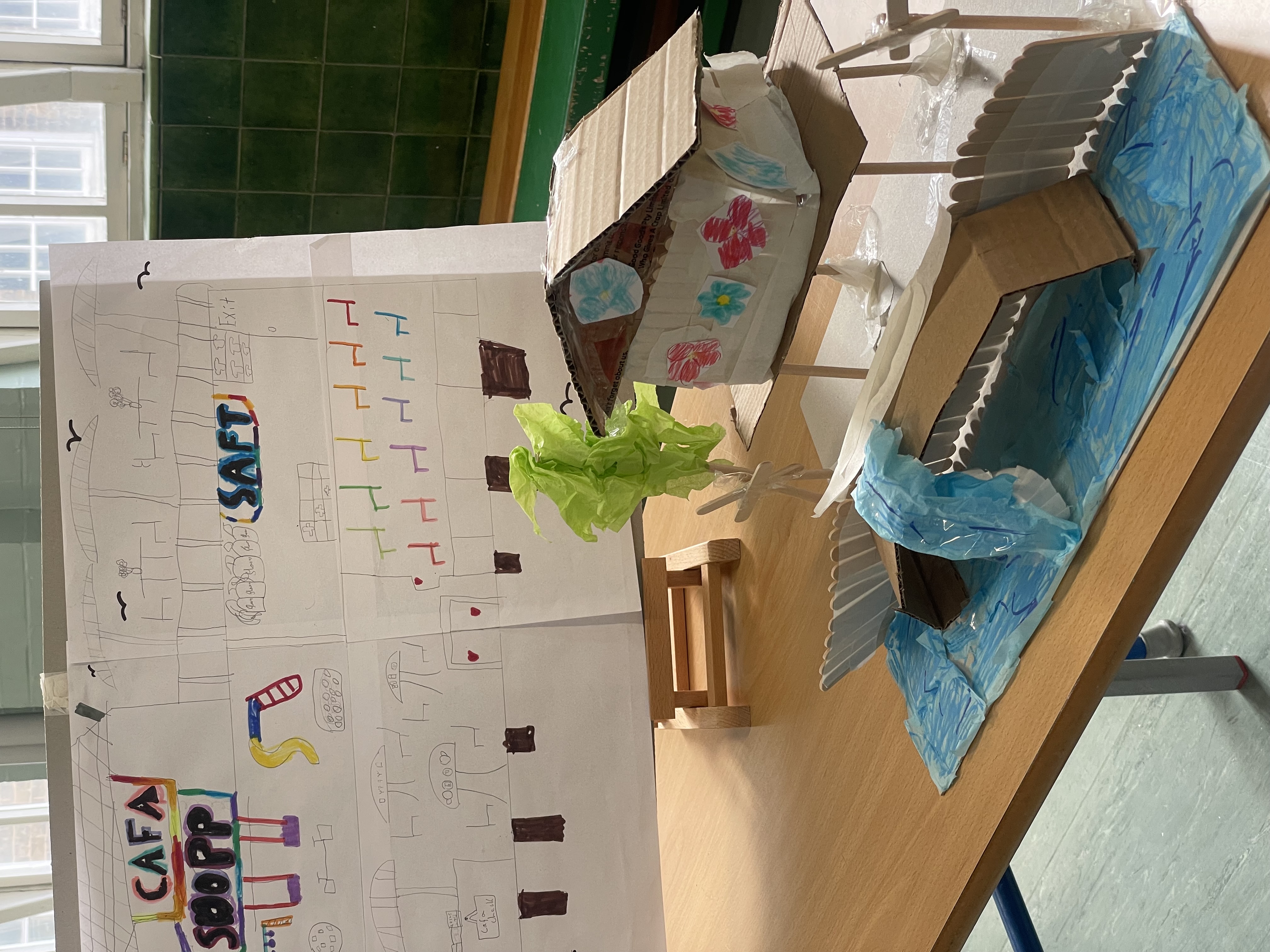 A close up photo of a student’s model. The model is of a building on stilts, above the sea decorated in floral motif.