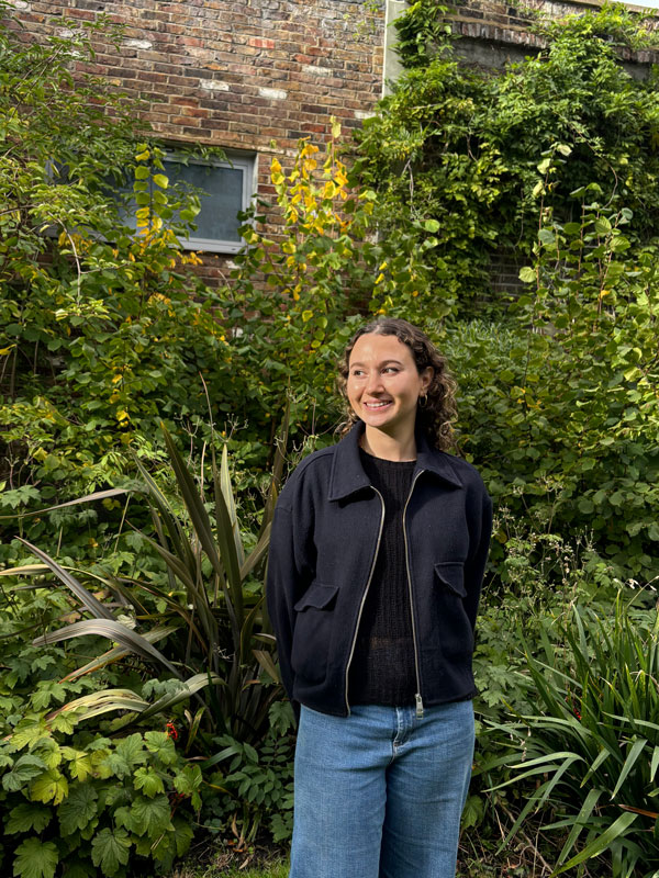 Jessica Smiling in front of vegetation in the garden.