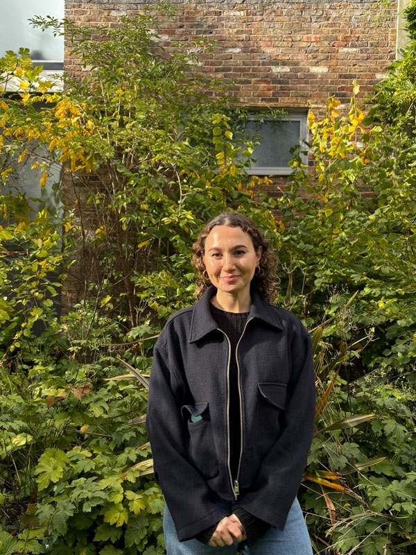 Jessica smiling at the camera in front of vegetation in the garden
