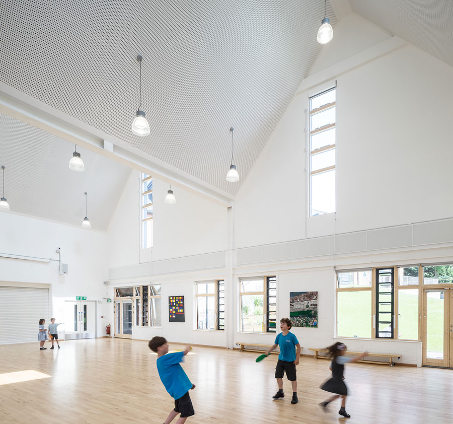 A photo illustrating where new additions meet the existing Victorian building. Black clad pitched roofs with double height windows mimic the historic form.