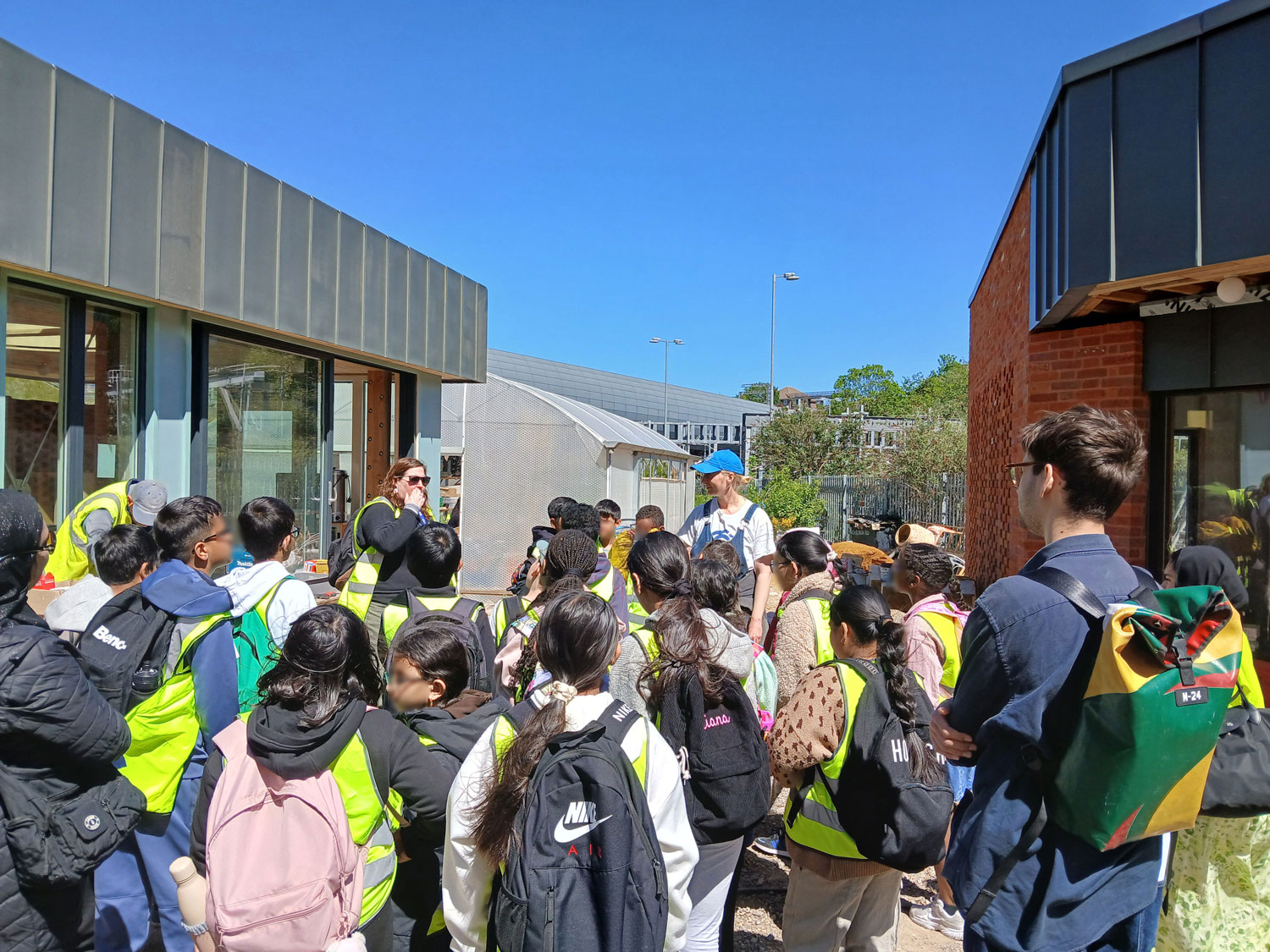 Our tour of the Triangle Site, students stand between two buildings while Alice gives a talk.