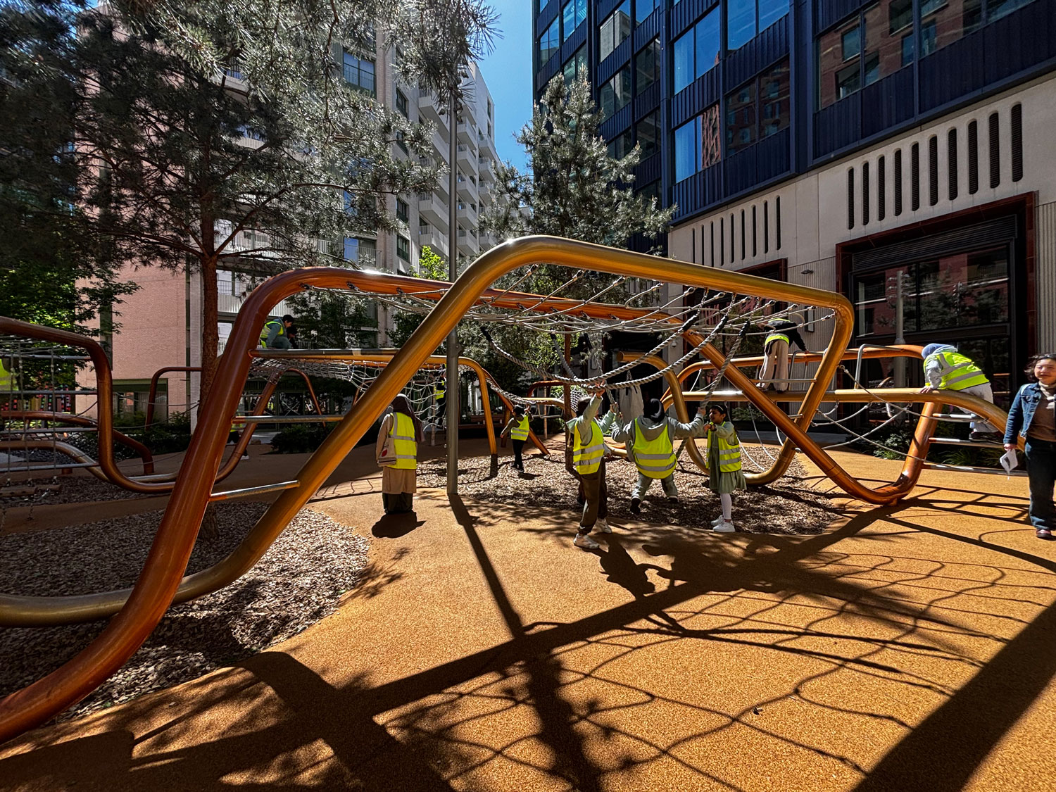 Students exploring the new Chilton Square Playground, they climb on the organic forms under the shade of a tree.