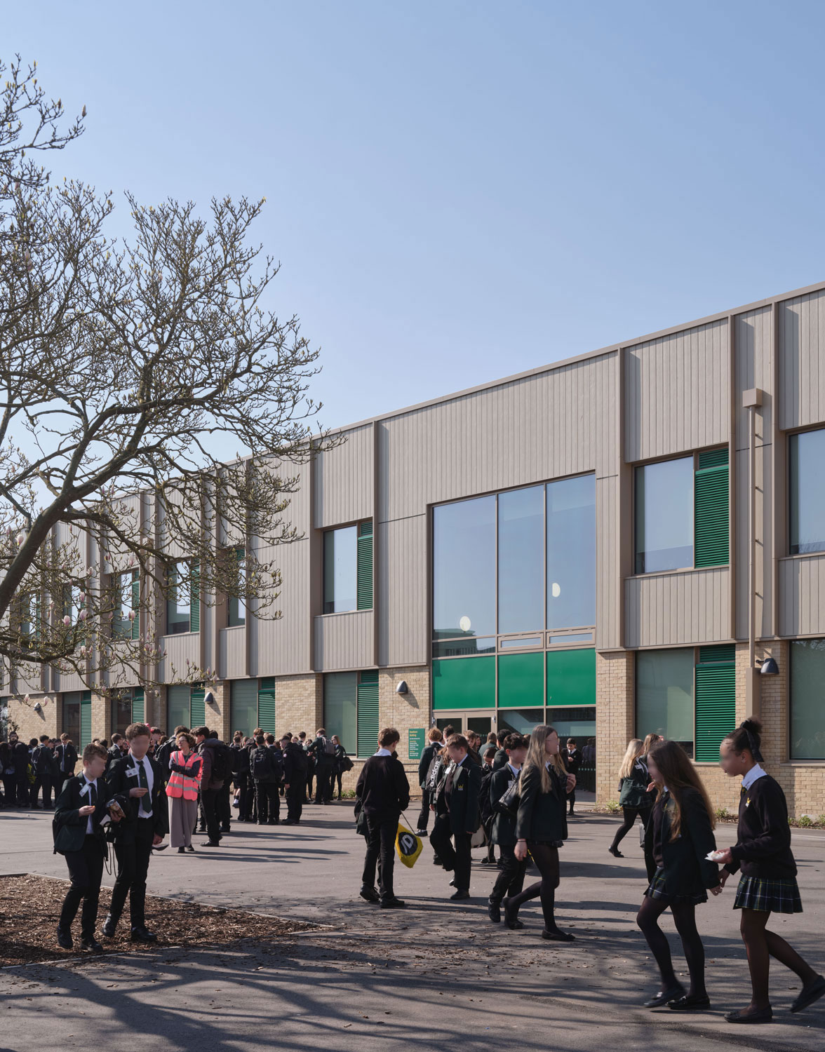 A photo of the entrance to the school. Students congregate and socialise outside.