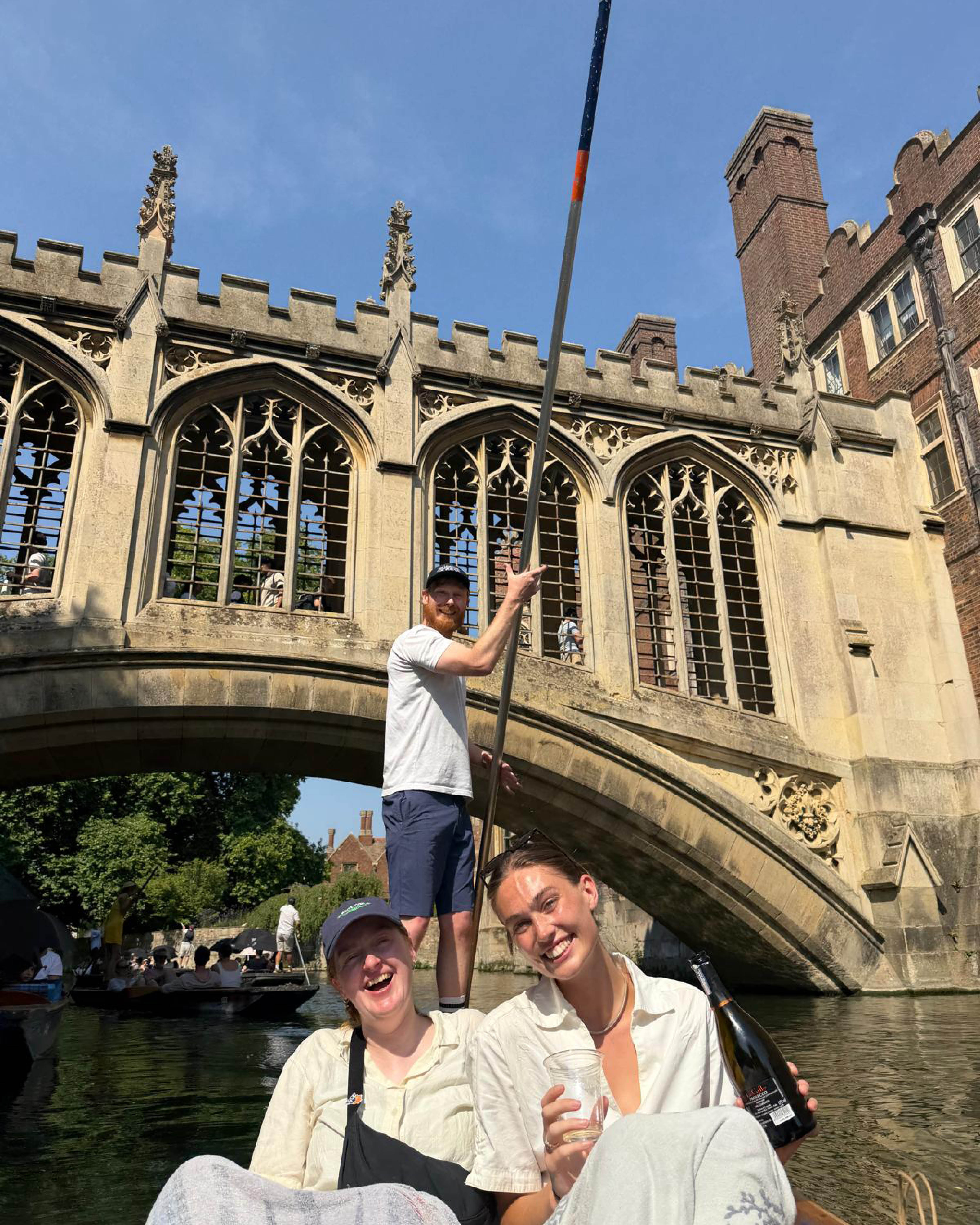 Three members of the team smile on a boat while punting.