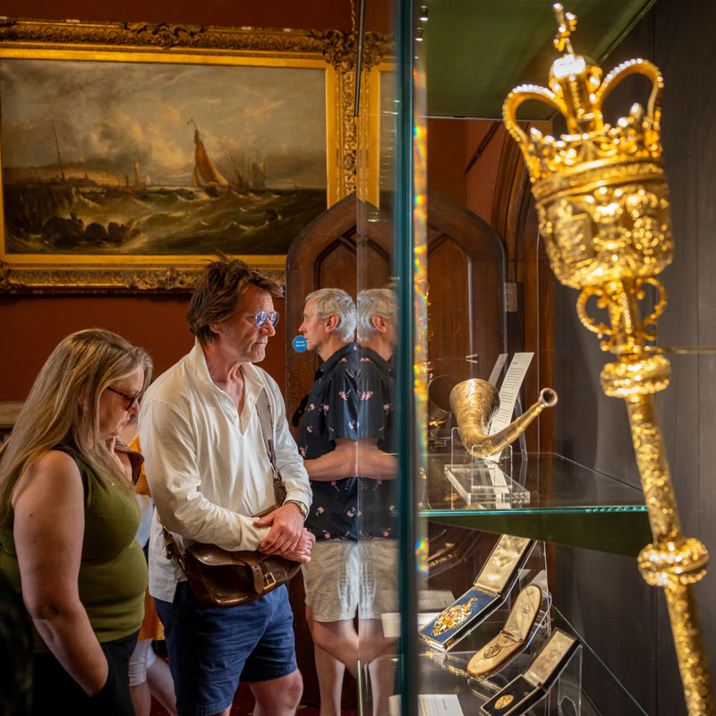 A man and a woman observe the artifacts in the Council Chamber.