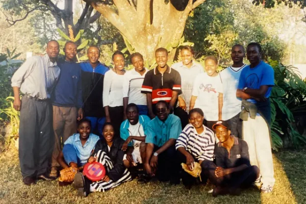 Diverse students and staff of Education Matters school pose under a Zimbabwean tree.