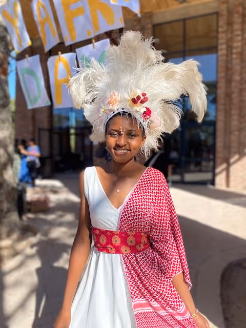 Happy Zimbabwean student in traditional attire stands outside Education Matters school in Africa.