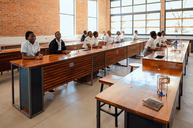 Students learning in a traditional Zimbabwe classroom setting with wooden desks and uniforms.