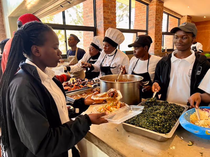 Students from Education Matters school in Zimbabwe Africa serving nutritious cafeteria meals together.