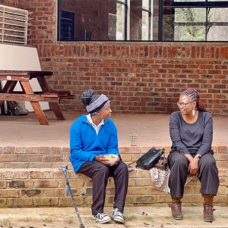 Women learning supporters sit outside Education Matters school in Zimbabwe, Africa's rural landscape.