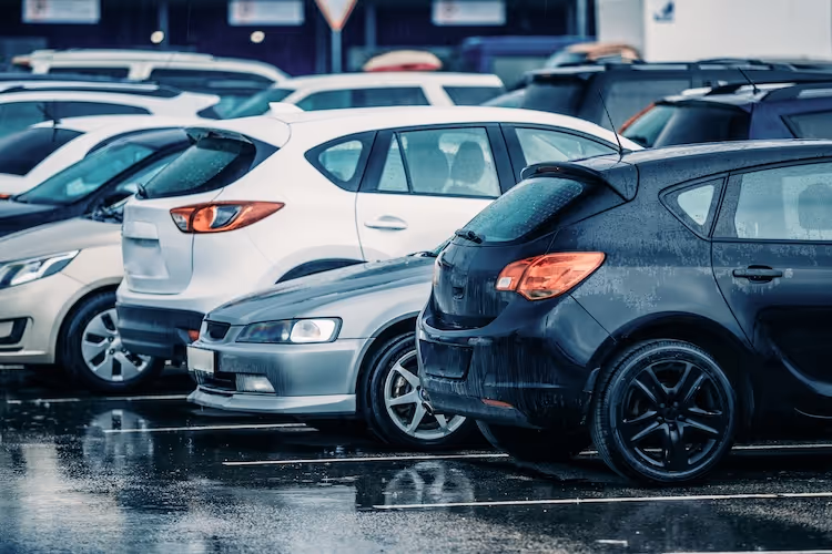 Wet parking lot filled with various modern cars in different colors
