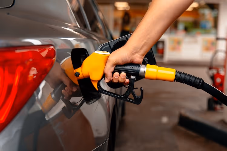 Hand refueling car with yellow gas pump at service station