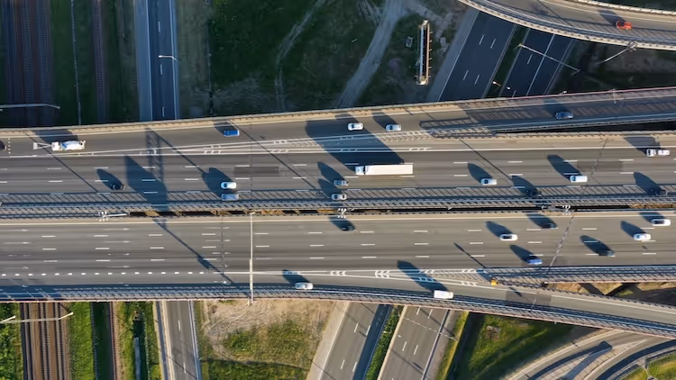 Aerial view of multi-lane highway interchange with cars and train tracks