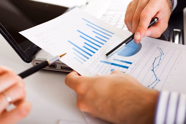 Business hands analyzing financial graphs and charts on paper