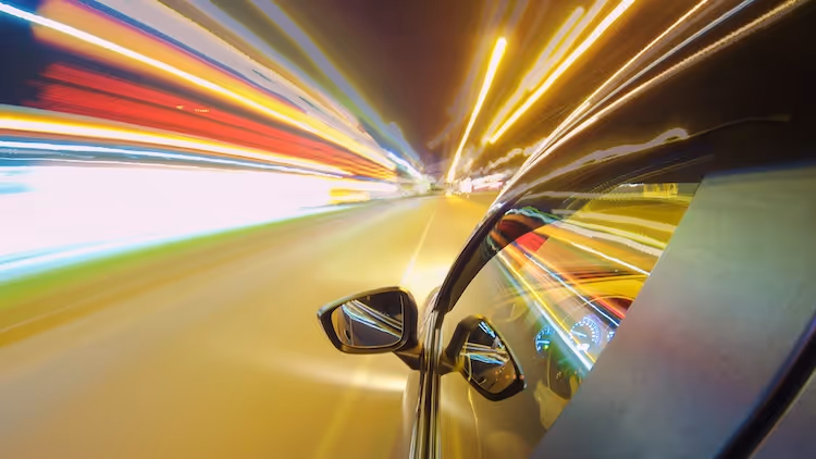 Car moving at high speed with blurred colorful light trails