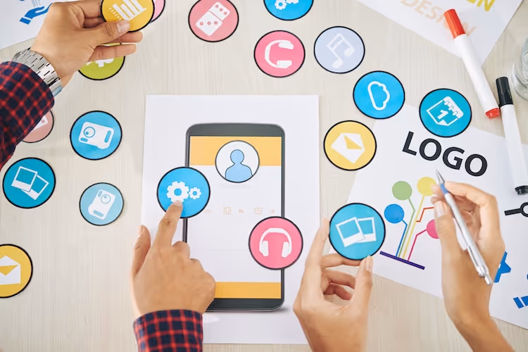 Hands arranging colorful app icons around smartphone during design brainstorming