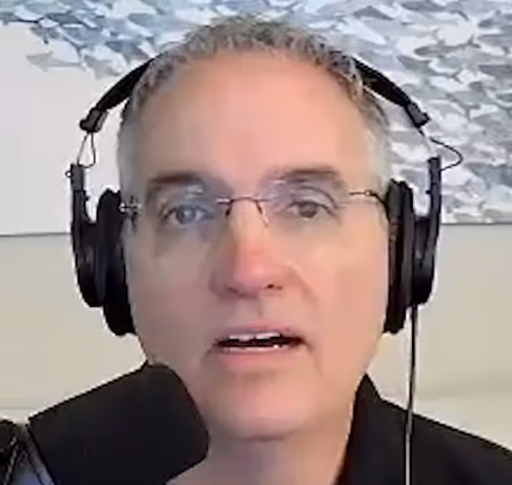 Person wearing headphones and glasses speaking into a microphone