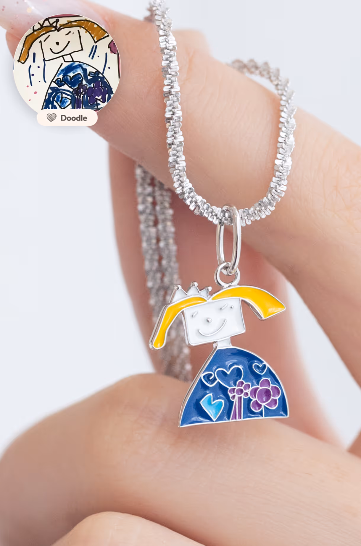 Handmade silver necklace with a pendant crafted from a child’s drawing of a girl in a blue dress and yellow hair.