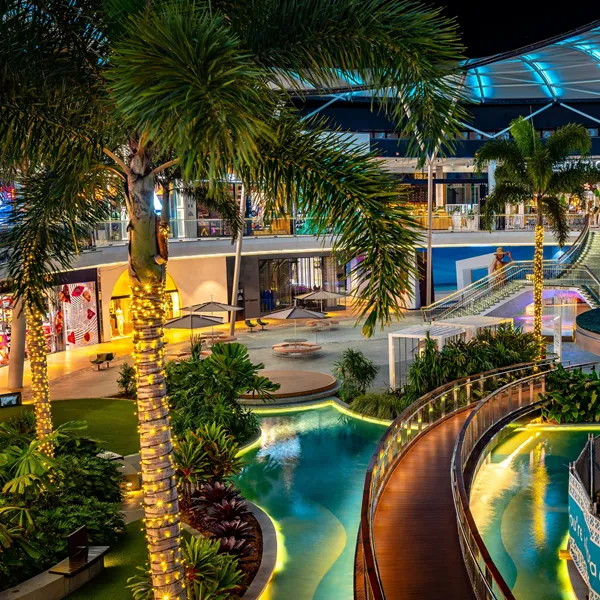 Bright modern interior room with terrazzo floor, wood-paneled wall with tall cabinets, glass sliding door revealing wooden stairs, and an open doorway to an outdoor space.
