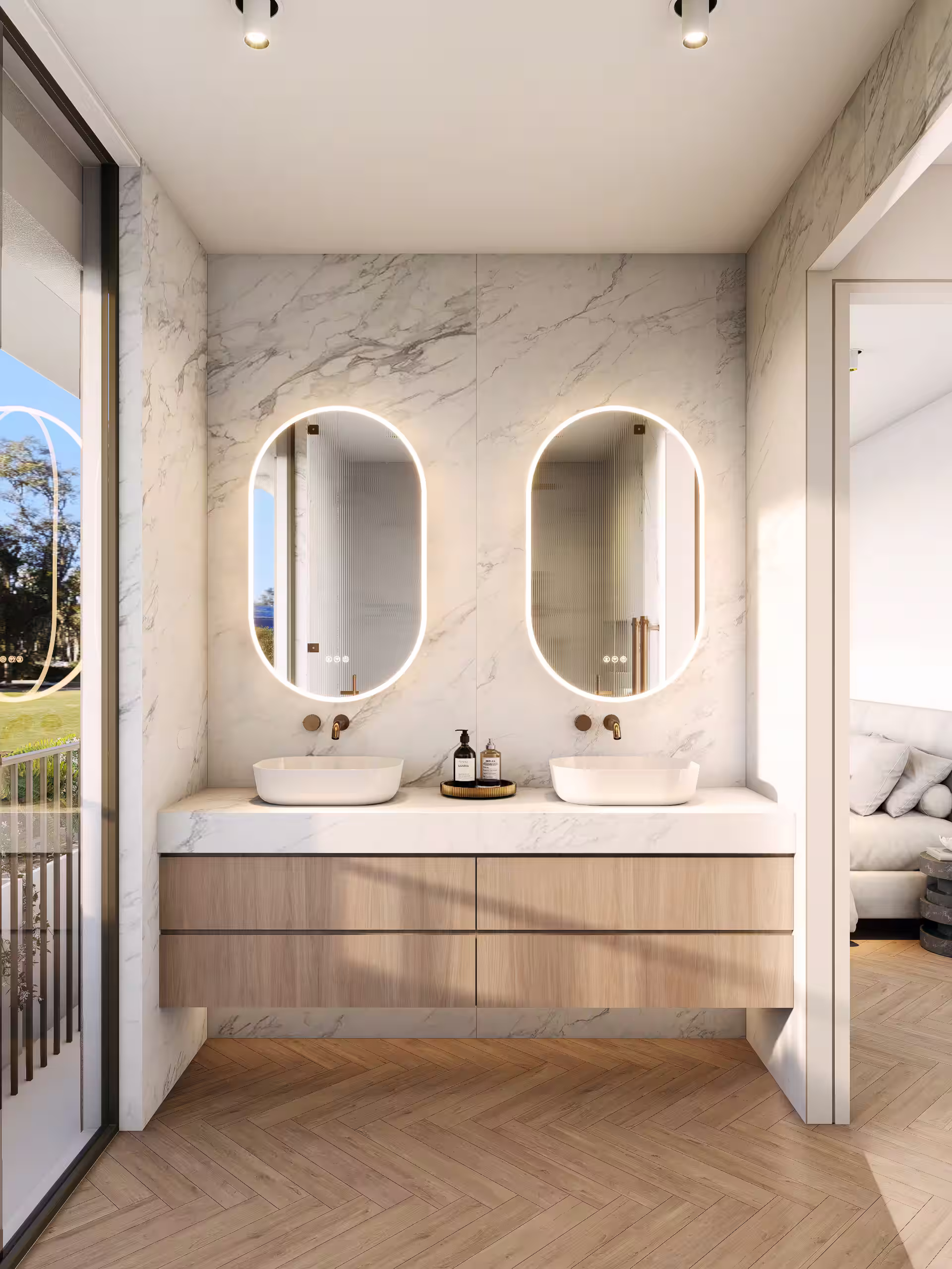 Modern bathroom vanity with two illuminated oval mirrors, white vessel sinks, and light wood cabinetry on a marble wall background.