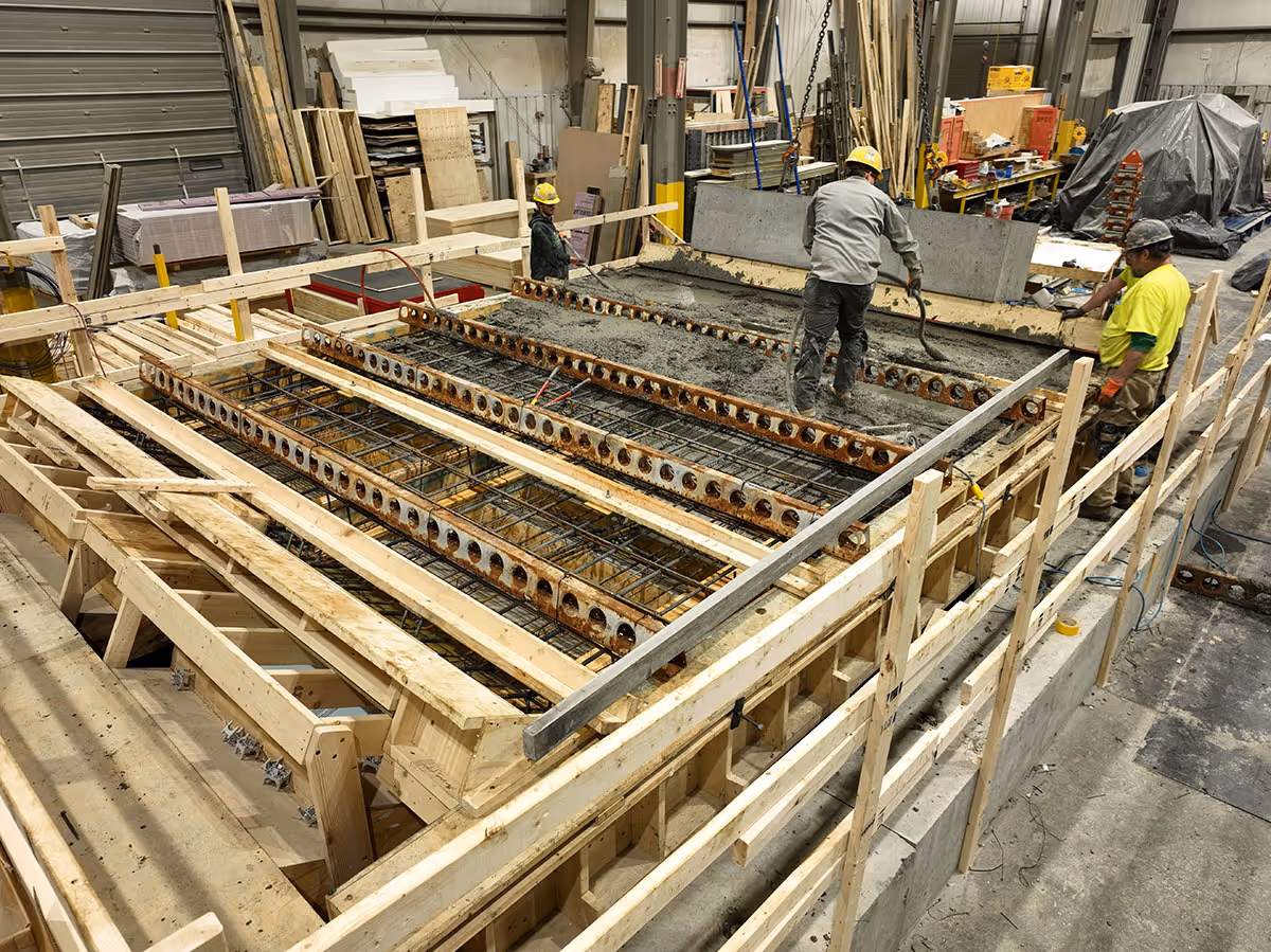 Brayman Preacst facility workers pouring concrete for precast concrete stairs over reinforcing bar