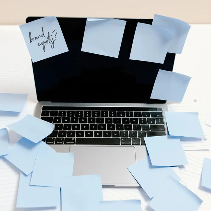 Computer with a bunch of blank post-it notes except for one with the question "Brand equity?" written on it.