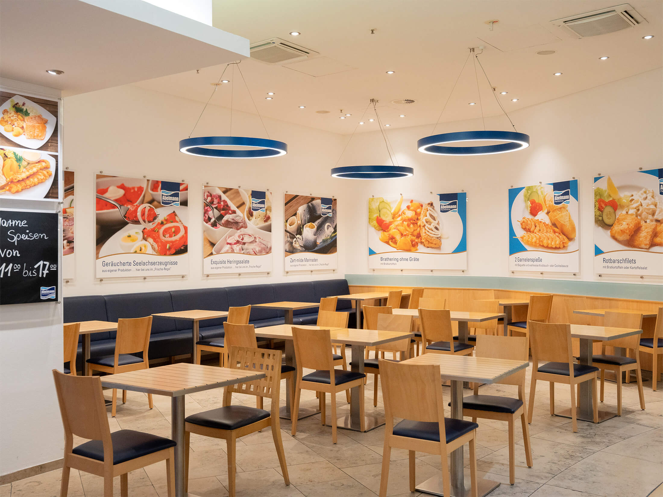 Heller und einladender Sitzbereich mit Wandbildern von Fischgerichten im Abelmann-Restaurant.