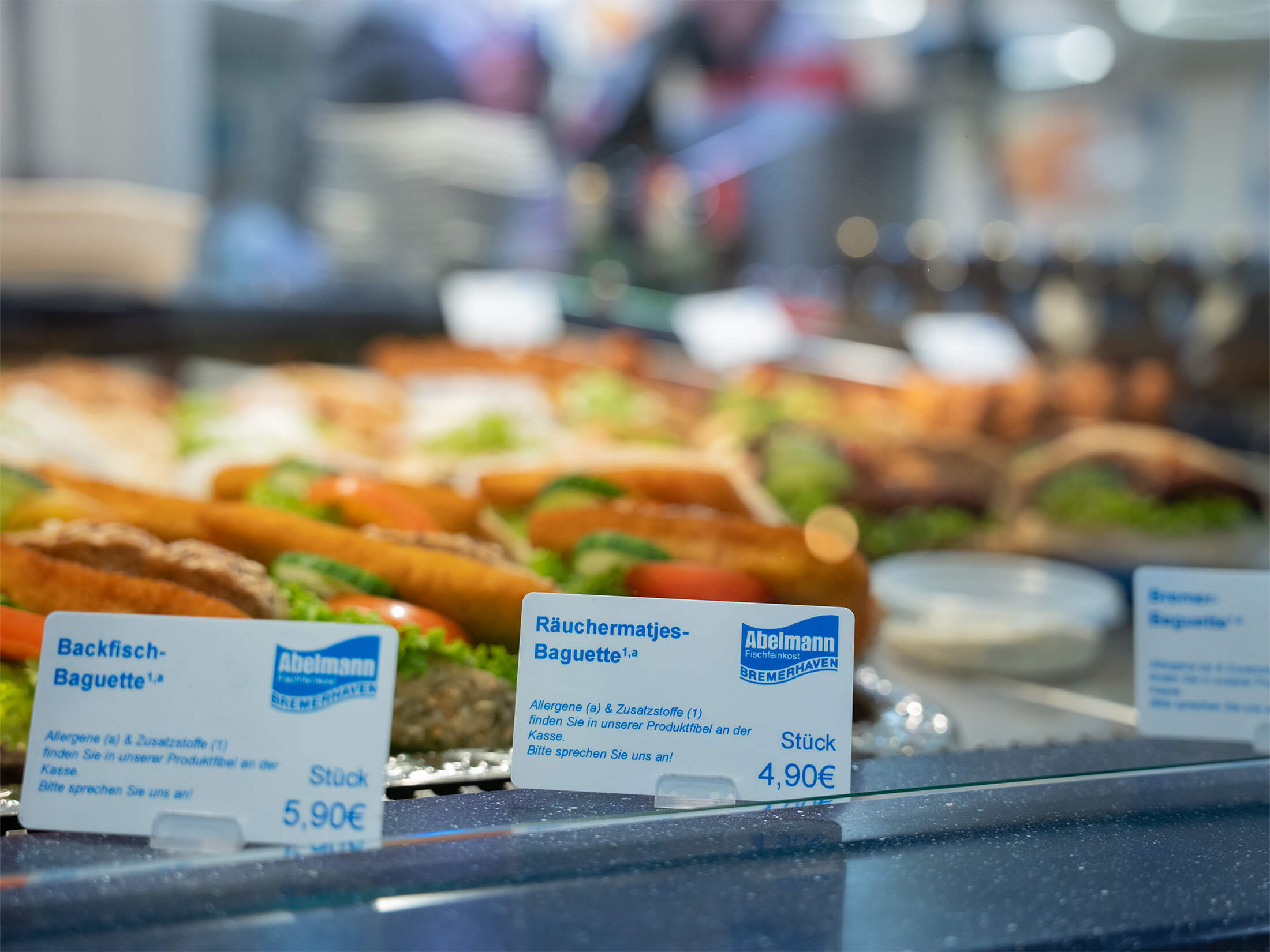 Nahaufnahme von frischen Fischbaguettes mit Etiketten und Preisen in der Auslage.