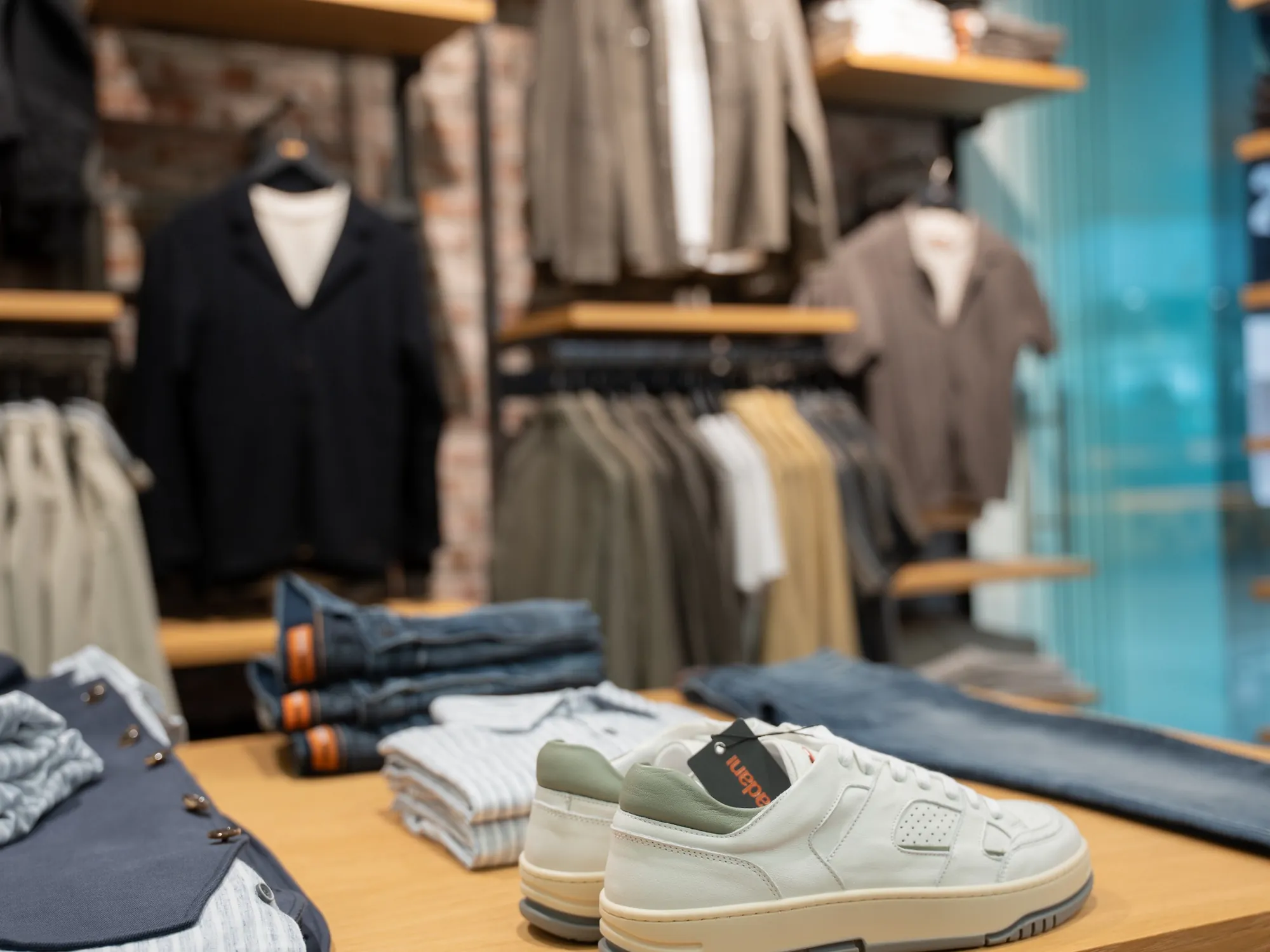 Herrenbekleidung, Jeans und Sneaker auf einem Präsentationstisch bei Engbers
