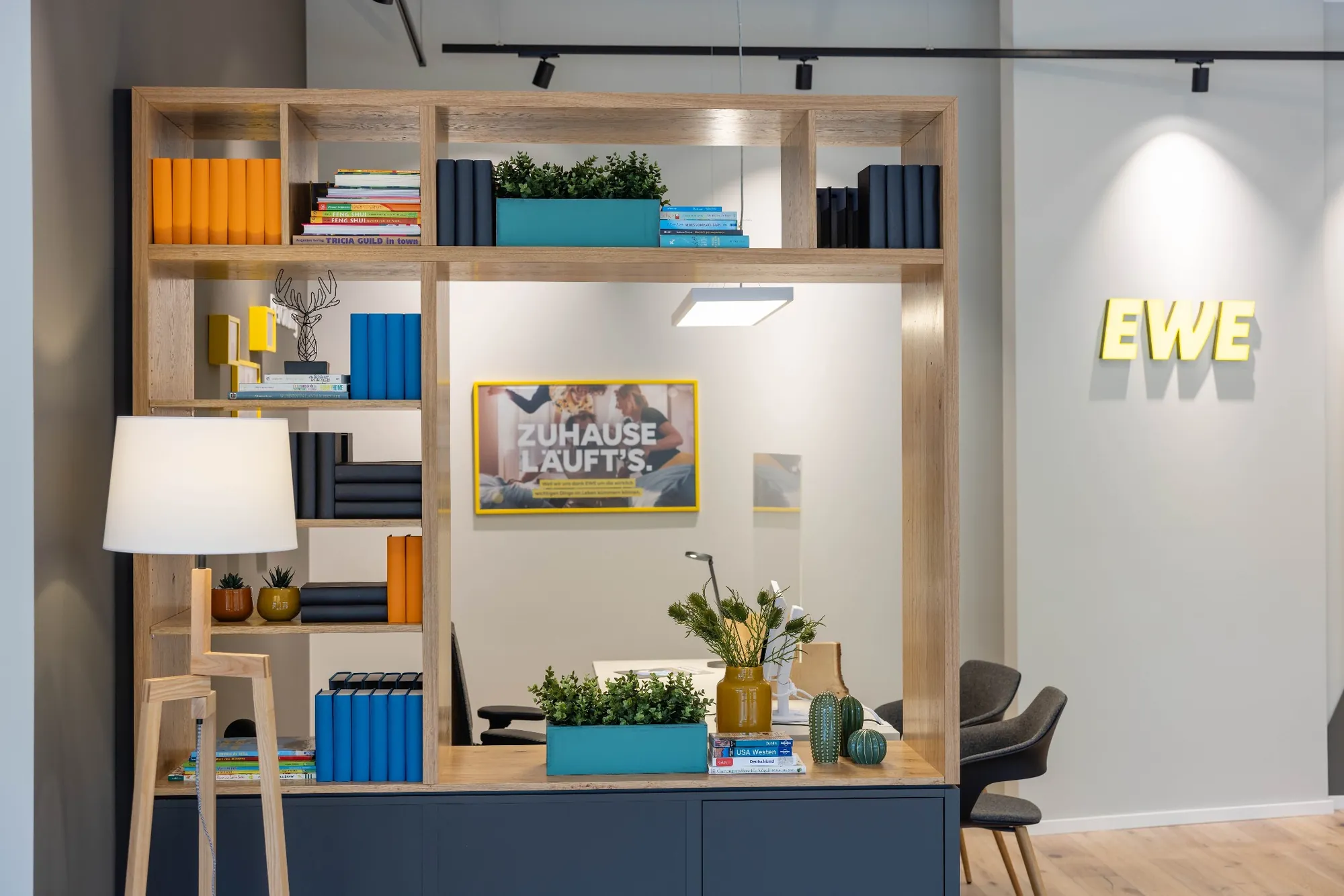 Beratungsplatz im EWE Shop mit Bücherregal, Pflanzen und Wandlogo