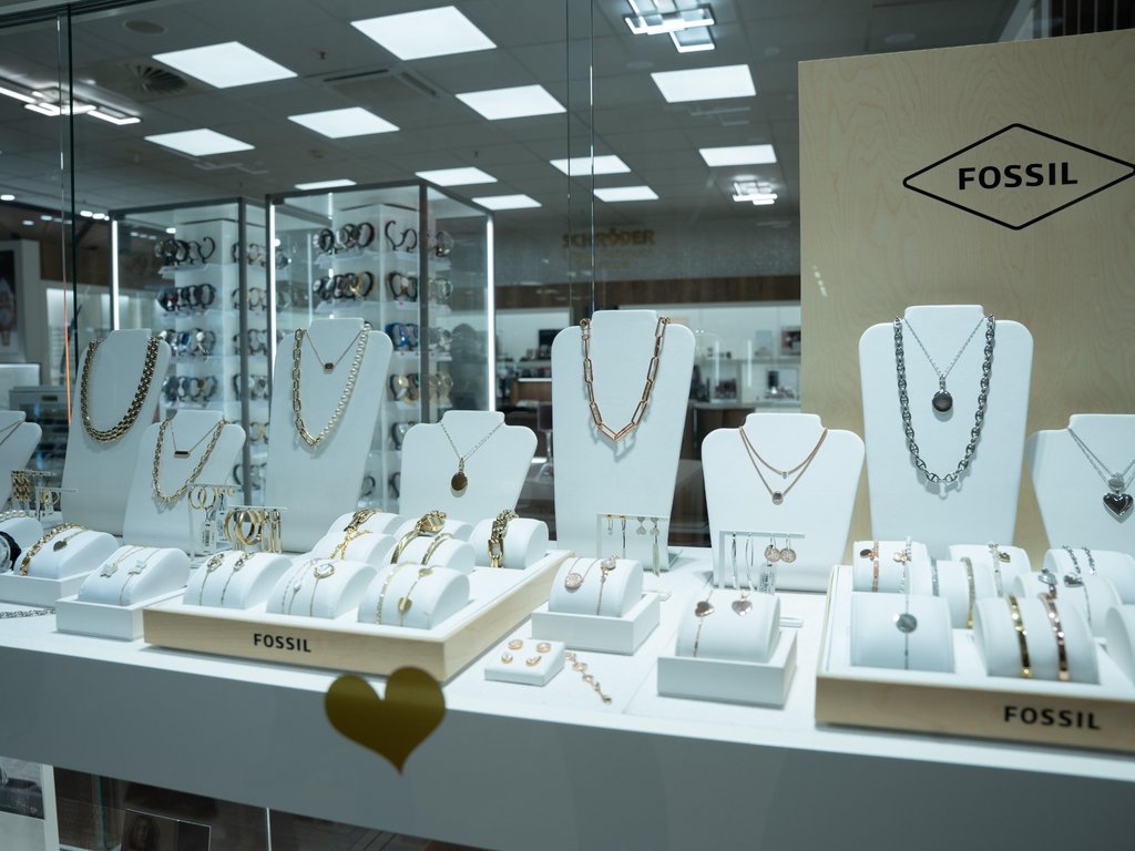 Fossil-Schmuckauslage mit Halsketten, Armbändern und Ohrringen in Gold und Silber