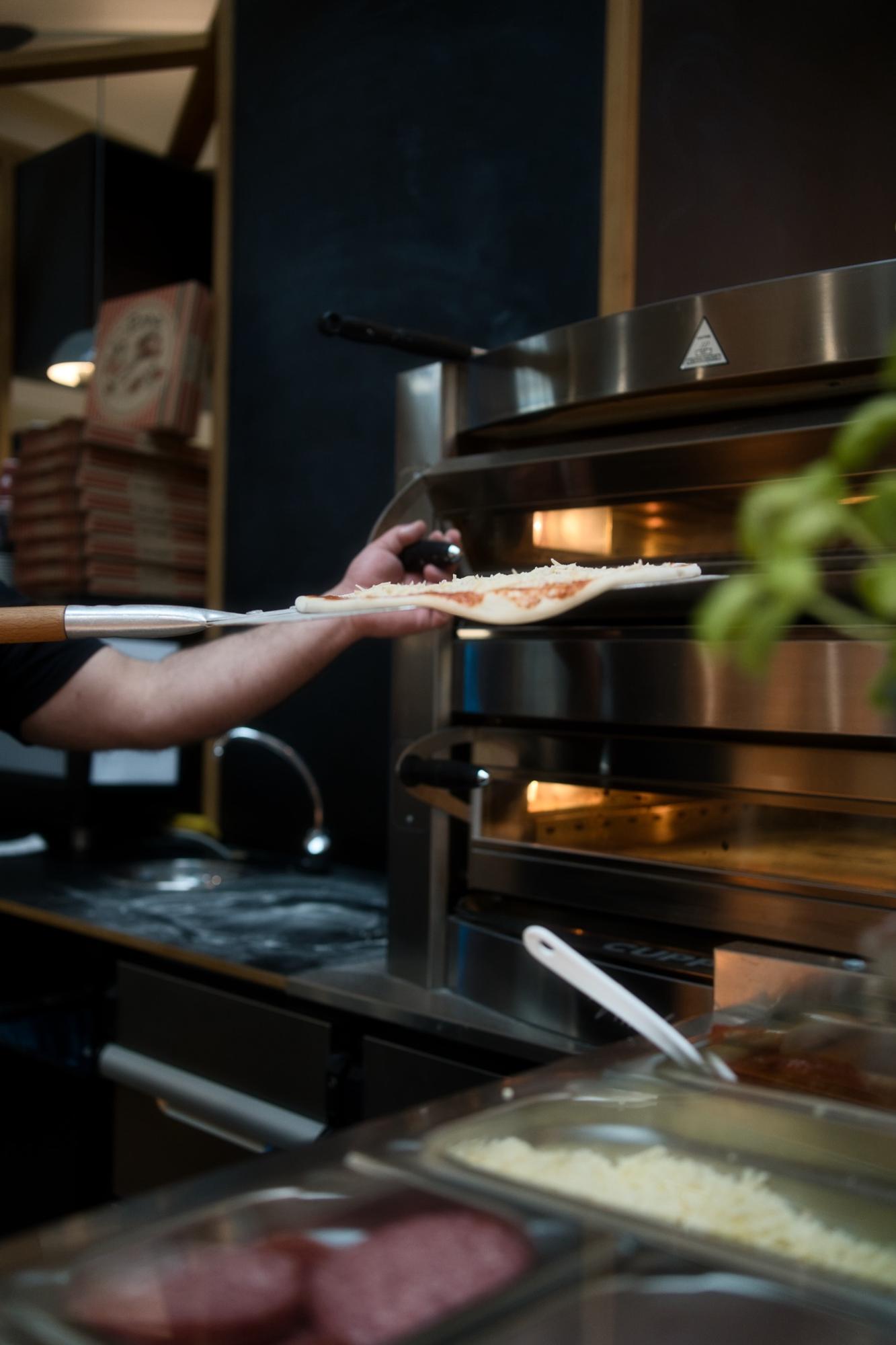 Pizza wird im Eiscafé Rimini in den heißen Ofen geschoben.