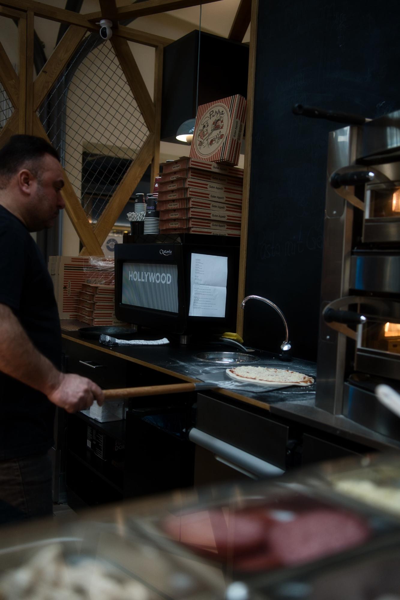 Pizzabäcker bereitet eine Pizza vor dem Ofen im Restaurant Rimini vor.