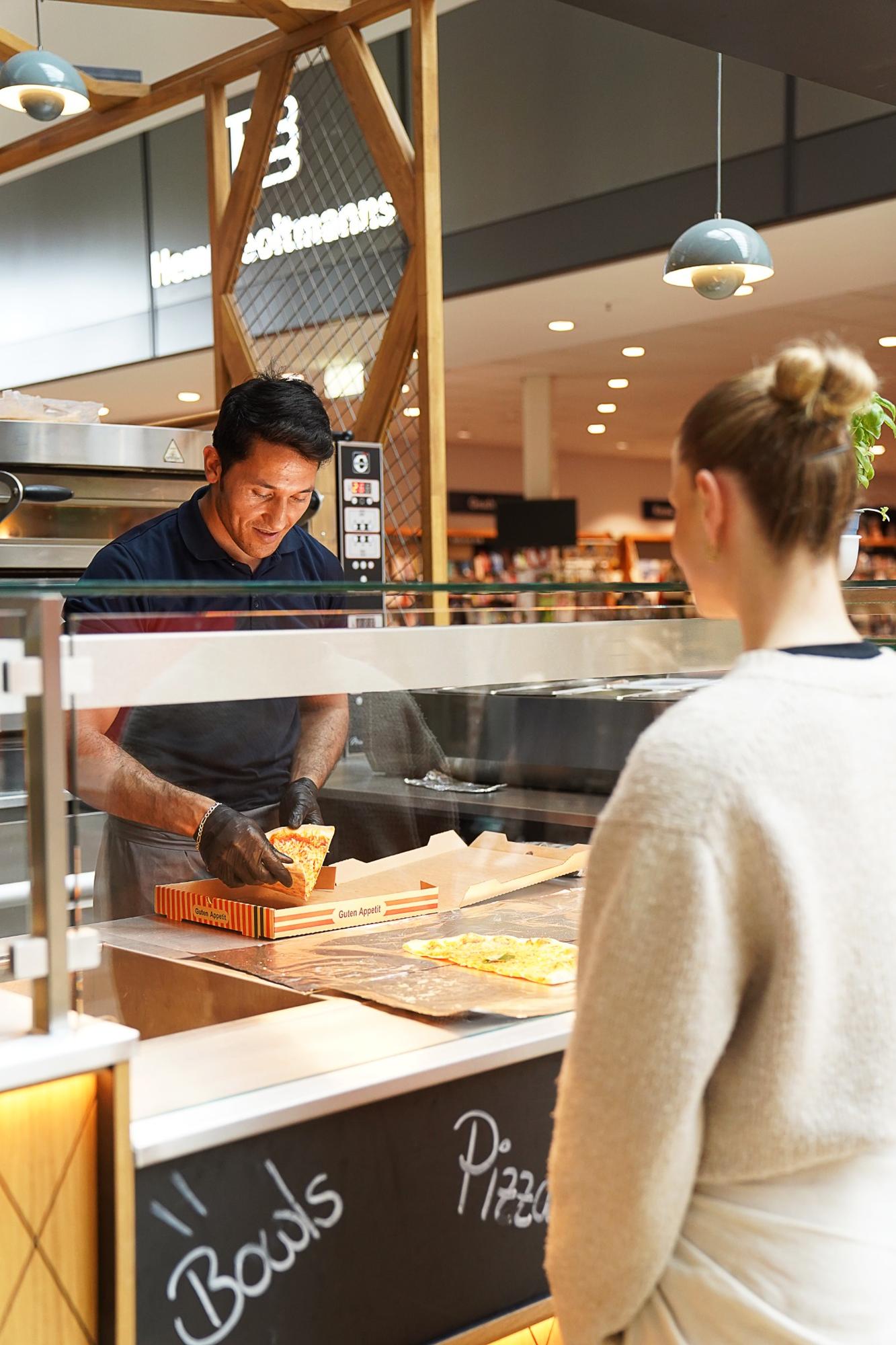 Kundin bestellt Pizza an der Theke im Eiscafé & Restaurant Rimini.